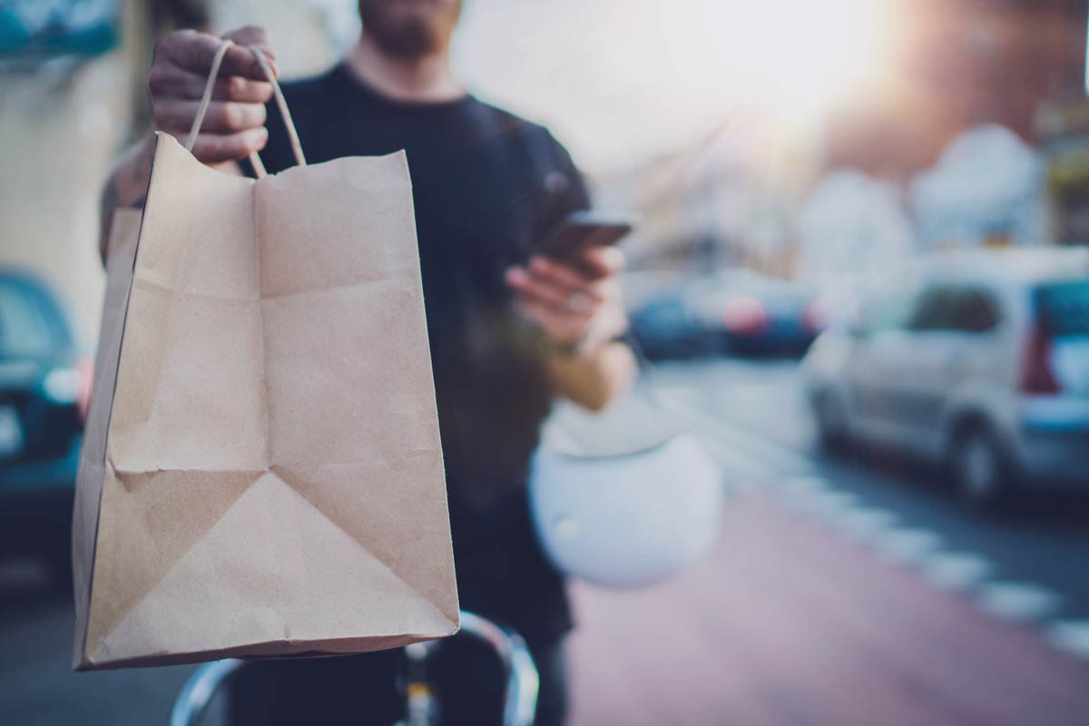 man on phone handing takeout bag