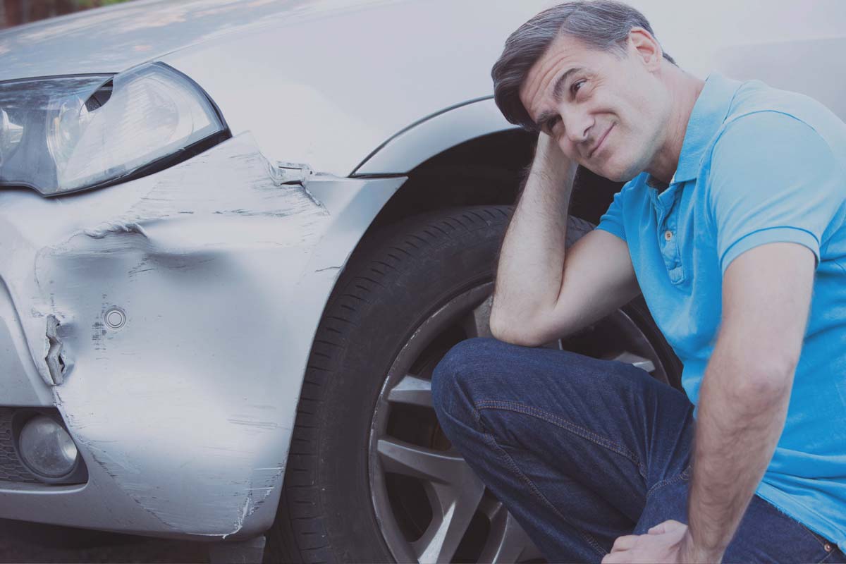 man frowning at damaged car